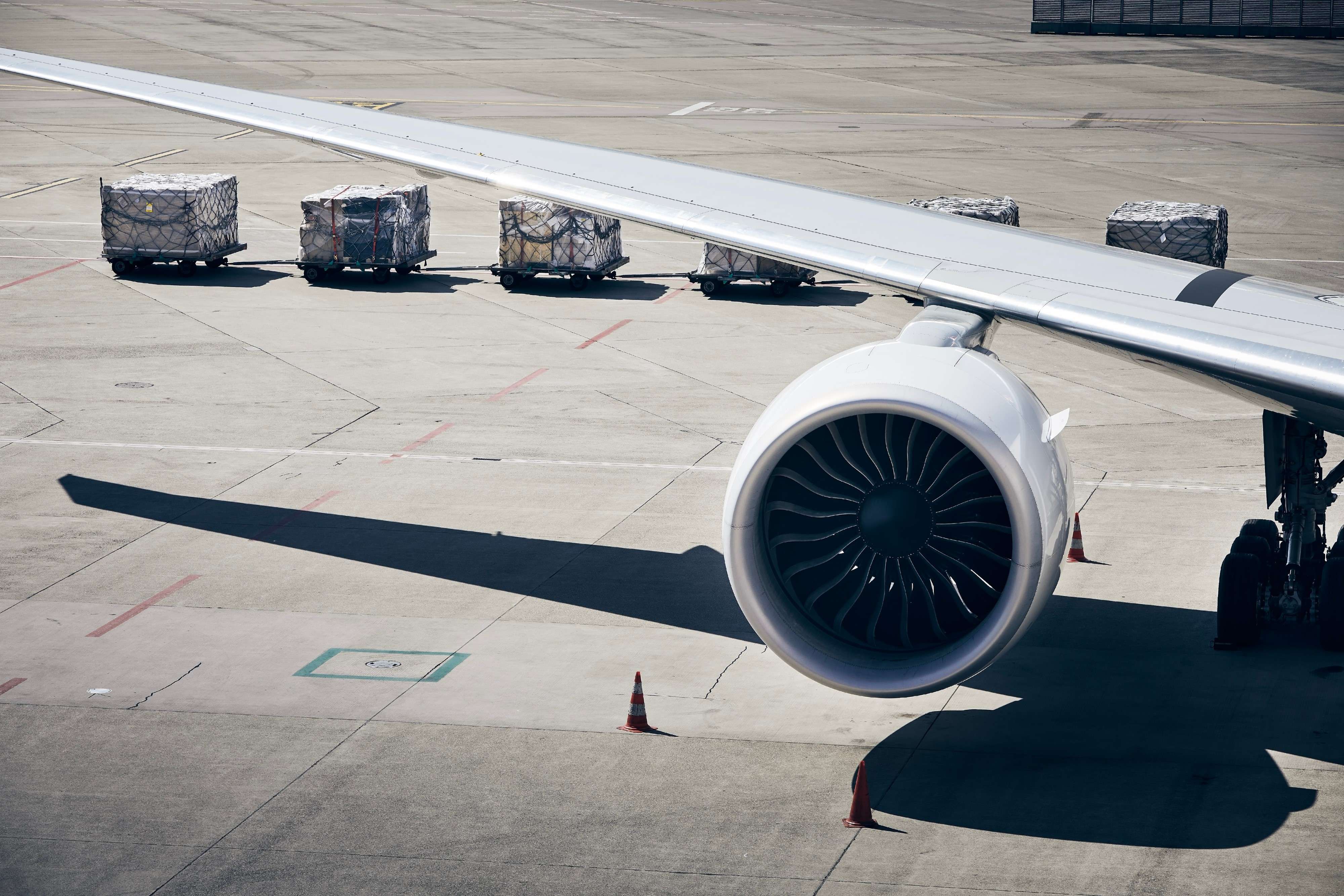 Loading of cargo containers to plane at airport. Ground handling preparing airplane before flight during sunny day.
