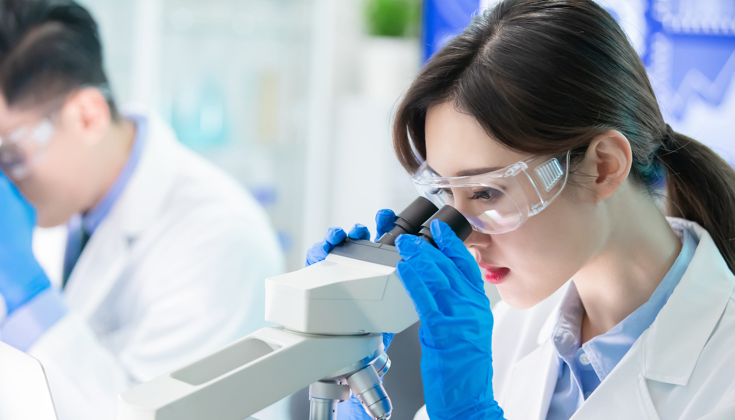 In a laboratory 2 specialists with a microscope creating biological products