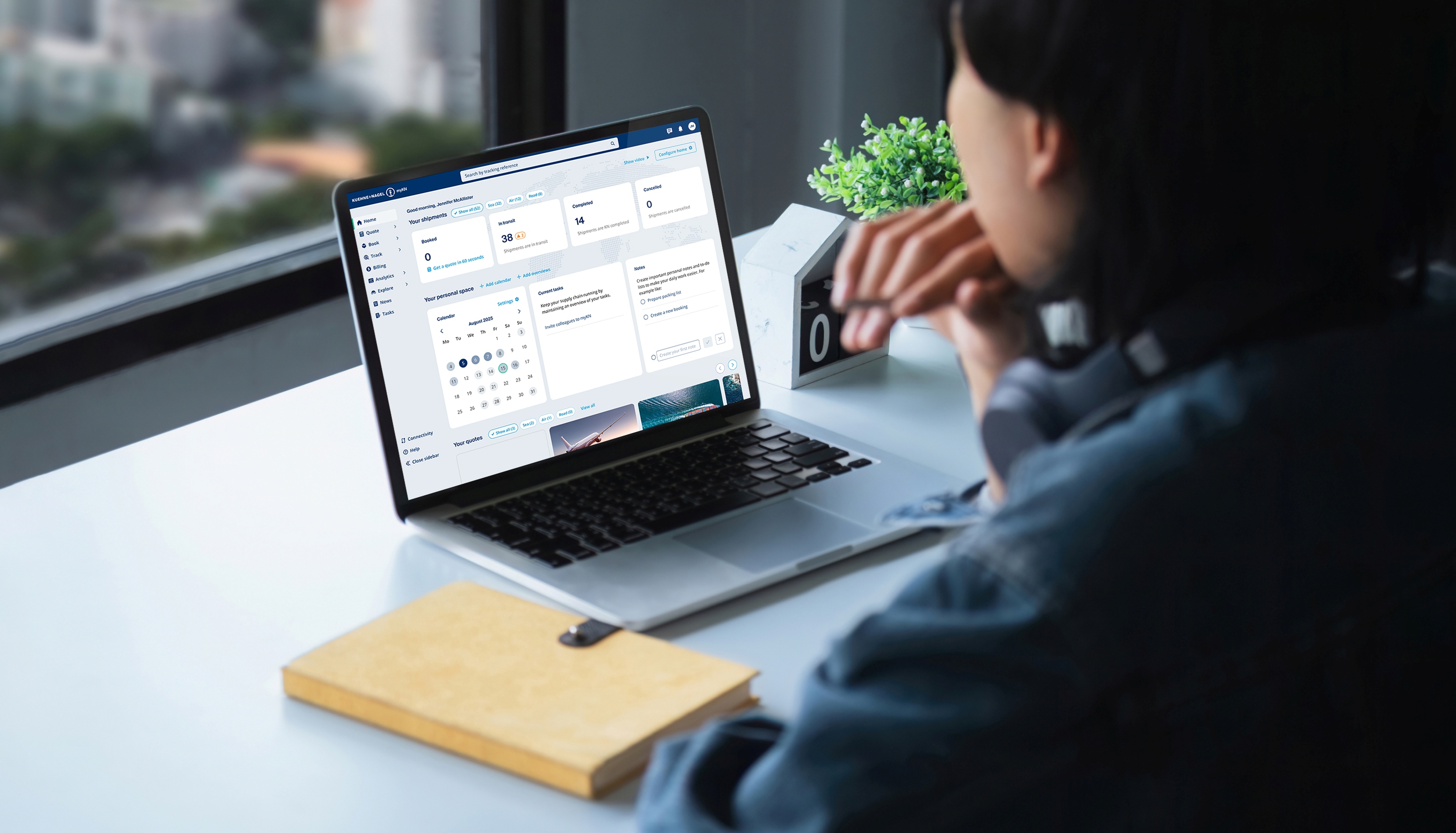 Person procuring freight rate on a laptop displaying a myKN interface, with a plant and desk accessories nearby.